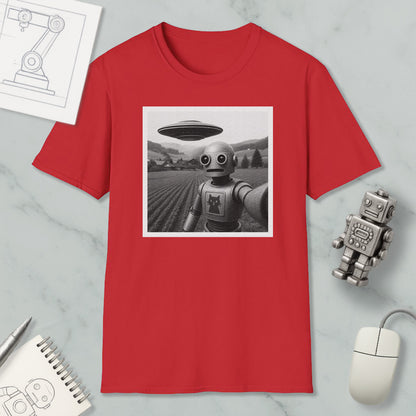 a red t-shirt with a black and white photograph of a robot and an alien spacecraft, along with various objects such as a notebook, a mouse, and a pen.