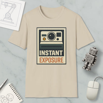 a beige t-shirt with a graphic design of a camera and the text "INSTANT EXPOSURE" printed on it, along with a small robot and a computer mouse.