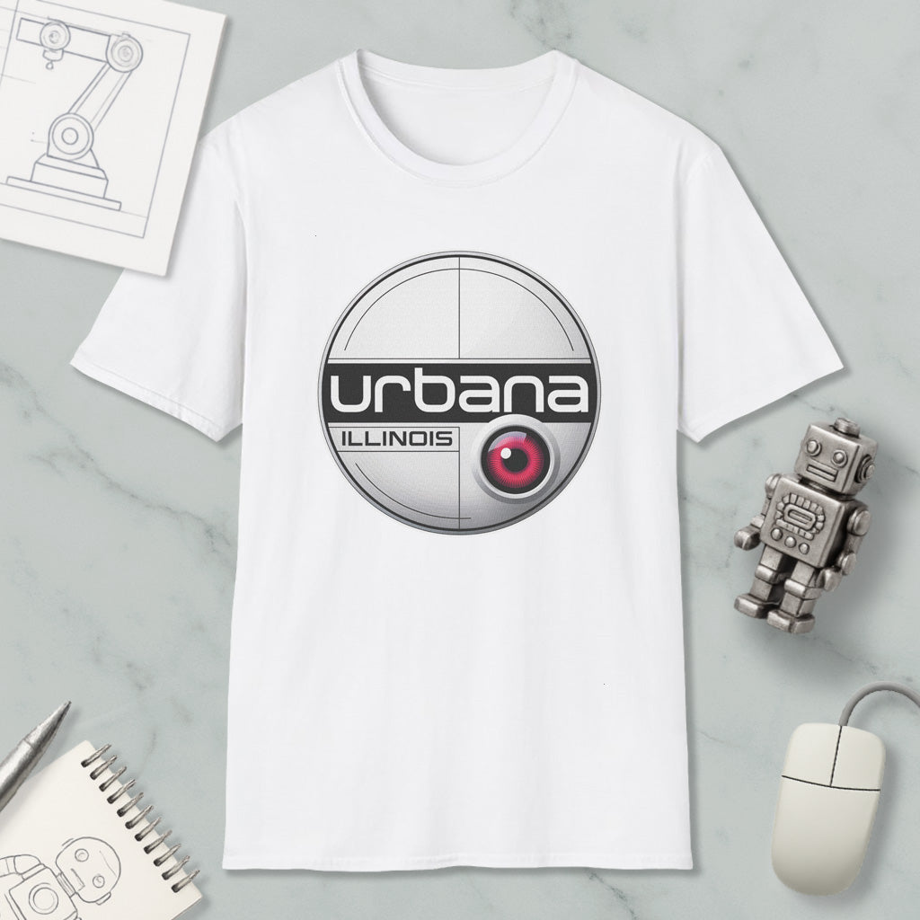 a white t-shirt with a circular logo, a computer mouse, a notebook, and a small robot on a marble surface.