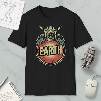 a black t-shirt with a graphic design of a robot or alien figure holding a sign that says "EARTH". The t-shirt is displayed on a marble surface, along with a computer mouse, a notebook, and a small robot figurine.
