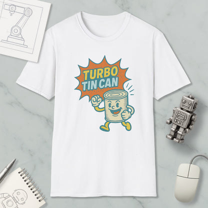 a white t-shirt with a graphic design depicting a tin can character with a speech bubble saying "TURBO TIN CAN". The t-shirt is placed on a marble surface, along with a computer mouse, a pen, and a notebook.