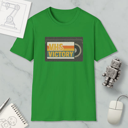 a green t-shirt with a graphic design, a computer mouse, a notebook, and a small robot on a marble surface.