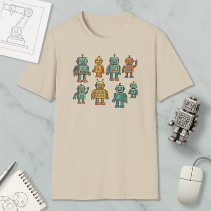 a beige t-shirt with a graphic design of nine colorful robots, including one robot with a yellow body and green arms. The t-shirt is placed on a marble surface, surrounded by various objects such as a computer mouse, a notebook, and a pen.