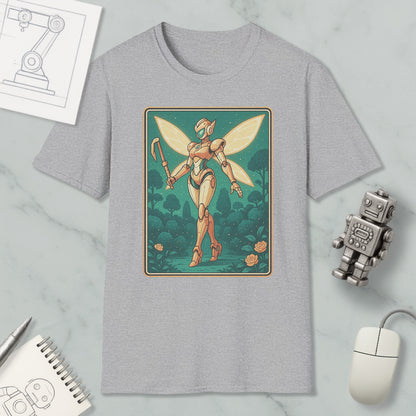 a gray t-shirt with a graphic design depicting a fairy-like robot or character with wings, standing in a forest-like setting. The t-shirt is placed on a marble surface, surrounded by various objects such as a computer mouse, a notebook, and a small robot figurine.
