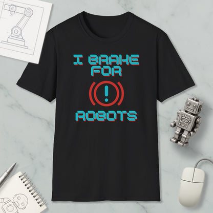 a black t-shirt with a humorous text design, a small robot, a computer mouse, and a notebook on a marble surface.
