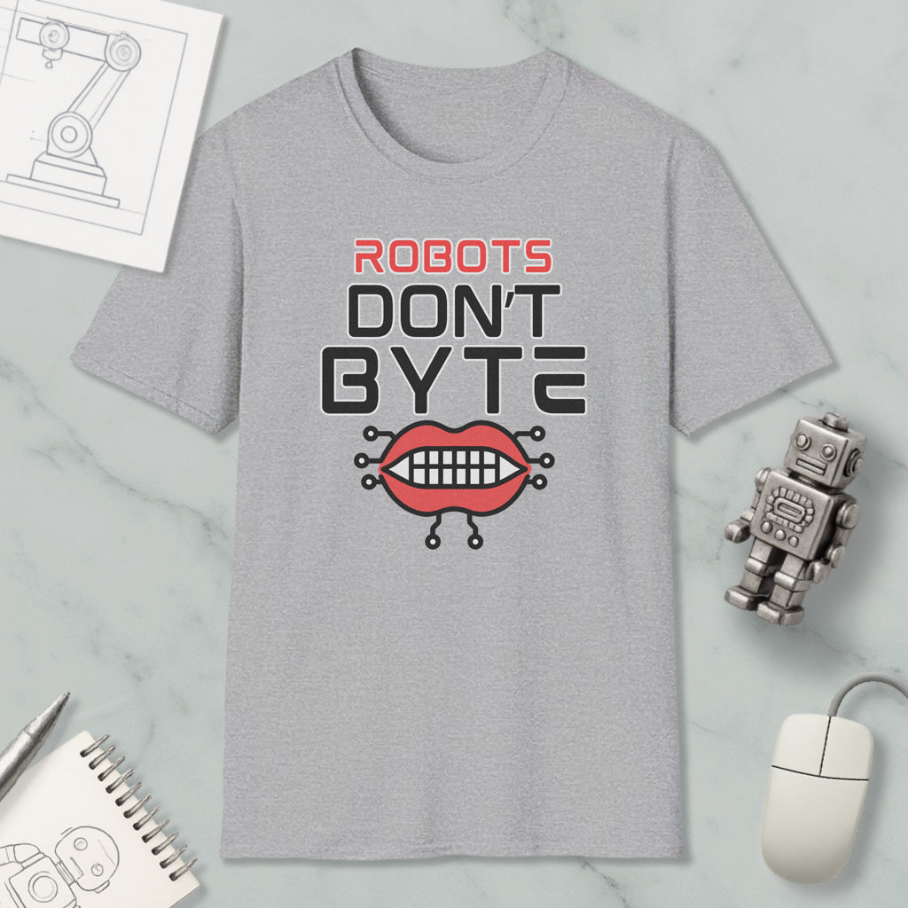 a gray t-shirt with a graphic design that says "ROBOTS DON'T BYTE" and includes a robot mouth with teeth. The t-shirt is placed on a marble surface, surrounded by various objects such as a computer mouse, a notebook, and a pen.