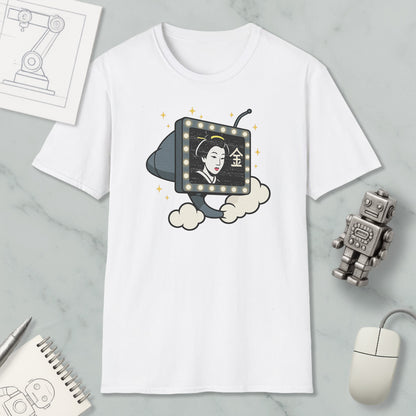 a white t-shirt with a graphic design depicting a woman's face on a television screen, surrounded by stars. The t-shirt is placed on a marble surface, with a computer mouse, a robot, and a notebook nearby.