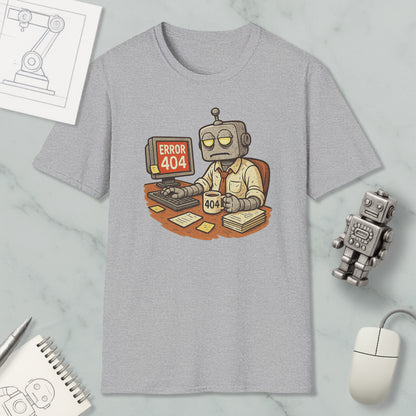 a gray t-shirt with a cartoon robot sitting at a desk, working on a computer, and displaying an error message that reads " Error 404". The t-shirt is surrounded by various objects, including a computer mouse, a pen, a notebook, and a small robot figurine.
