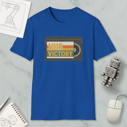 a blue t-shirt with a graphic design, a computer mouse, a notebook, and a small robot on a marble surface.