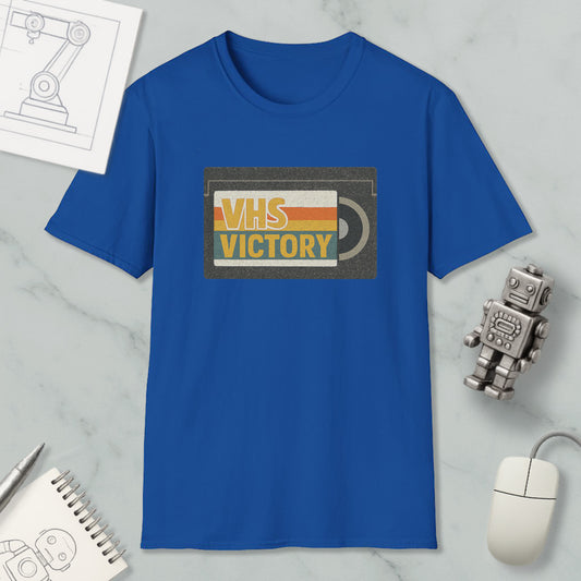 a blue t-shirt with a graphic design, a computer mouse, a notebook, and a small robot on a marble surface.