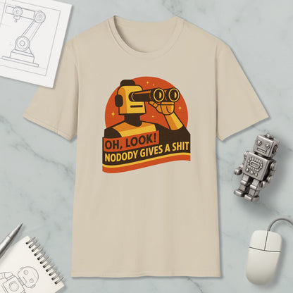 a beige t-shirt with a graphic design depicting a robot character looking through binoculars and holding a sign that says "OH, LOOK! NODODY GIVES A SHIT". The t-shirt is displayed on a marble surface, along with a computer mouse, a pen, and a notebook.