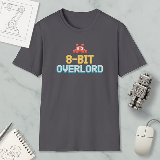 a gray t-shirt with a pixelated robot and text, along with various objects such as a computer mouse, a notebook, and a robot figurine.