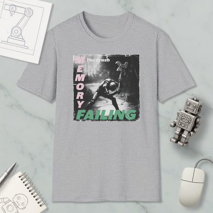a grey t-shirt with a graphic design depicting a person in a robot-like pose, along with the text "The crash memory failing". The t-shirt is displayed on a marble surface, accompanied by various objects such as a computer mouse, a notebook, and a robot figurine.
