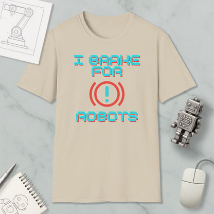 a beige t-shirt with the text "I brake for robots" printed on it, along with a red exclamation mark symbol. The t-shirt is placed on a marble surface, and there are various objects such as a computer mouse, a robot toy, and a notebook nearby.