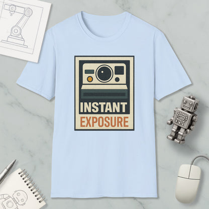 a light blue t-shirt with a graphic design of a camera and the text "INSTANT EXPOSURE" printed on it, along with a small robot toy and a computer mouse.