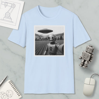 a light blue t-shirt with a black and white photograph of a robot standing in a field, with a spaceship flying above it. The t-shirt is displayed on a marble surface, along with a small robot figurine and a computer mouse.