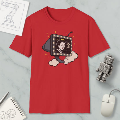 a red t-shirt with a graphic design depicting a woman's face on a television screen, surrounded by clouds and stars. The t-shirt is placed on a marble surface, with a computer mouse, a robot, and a notebook nearby.