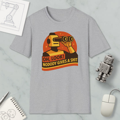 a gray t-shirt with a graphic design depicting a robot character looking through binoculars and holding a sign that says "OH, LOOK! NODODY GIVES A SHIT". The t-shirt is displayed on a marble surface, along with a computer mouse, a pen, and a notebook.