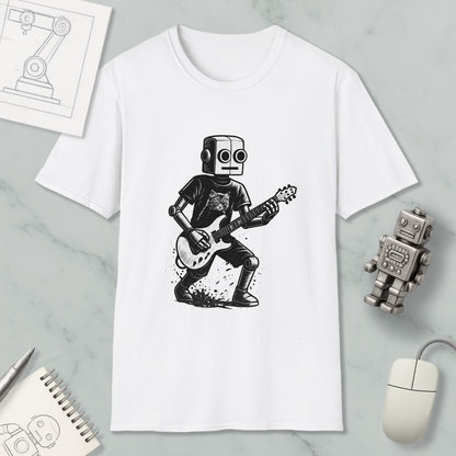 a white t-shirt with a black and white illustration of a robot playing a guitar. The t-shirt is placed on a marble surface, surrounded by various objects such as a computer mouse, a notebook, and a small robot figurine.