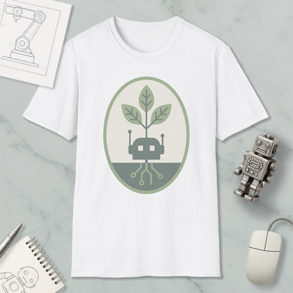 a white t-shirt with a graphic design of a plant growing out of a circuit board, surrounded by a green and gray oval. The t-shirt is placed on a marble surface, along with a small robot toy, a computer mouse, and a notebook.