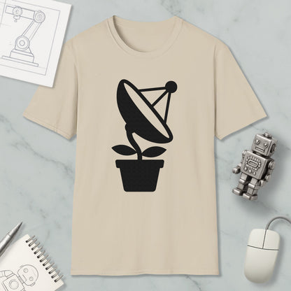 a beige t-shirt with a black satellite dish graphic, a small robot, a mouse, and a notebook on a marble surface.