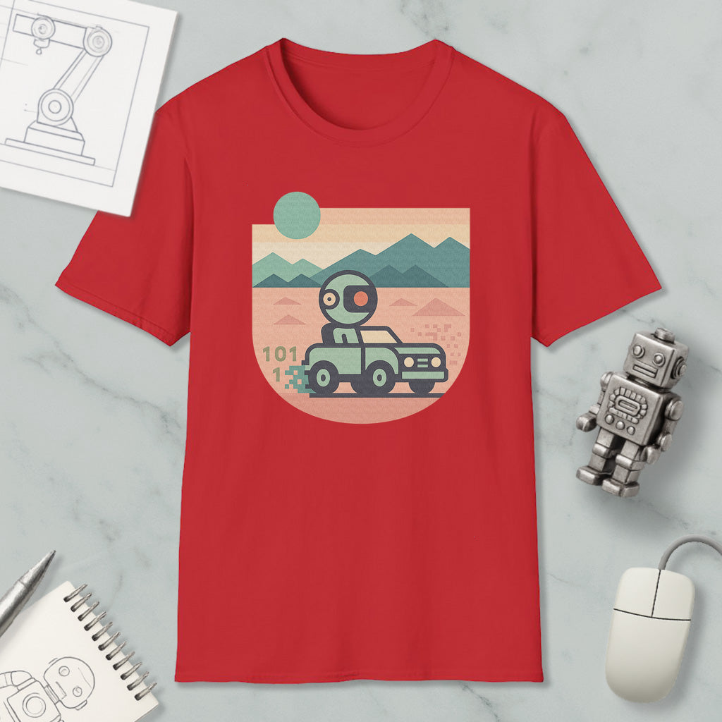 a red t-shirt with a graphic design depicting a robot driving a car on a desert road, surrounded by mountains. The t-shirt is placed on a marble surface, with a computer mouse, a pen, and a notebook nearby.