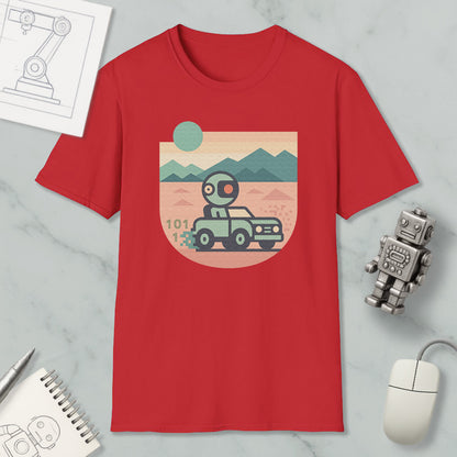 a red t-shirt with a graphic design depicting a robot driving a car on a desert road, surrounded by mountains. The t-shirt is placed on a marble surface, with a computer mouse, a pen, and a notebook nearby.