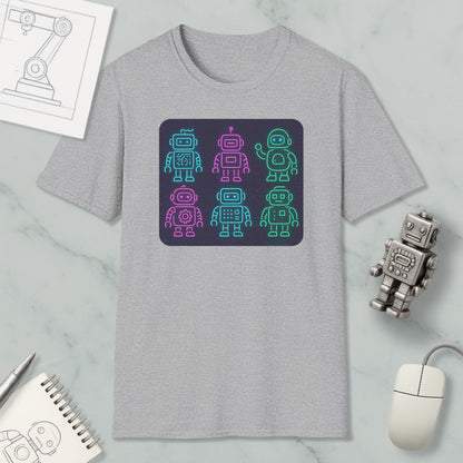 a gray t-shirt with a graphic design of six colorful robot icons arranged in a square pattern. The t-shirt is placed on a marble surface, surrounded by various objects such as a computer mouse, a notebook, and a pen.
