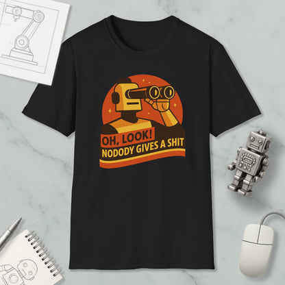 a black t-shirt with a graphic design depicting a robot character and the text "OH, LOOK! NODODY GIVES A SHIT" printed on it. The t-shirt is displayed on a marble surface, along with a computer mouse, a pen, and a notebook.