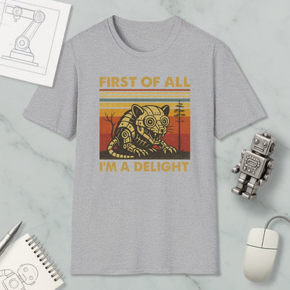 a gray t-shirt with a graphic design of a robot and the text "FIRST OF ALL I'M A DELIGHT" printed on it. The t-shirt is placed on a marble surface, along with a computer mouse, a notepad, and a small robot figurine.