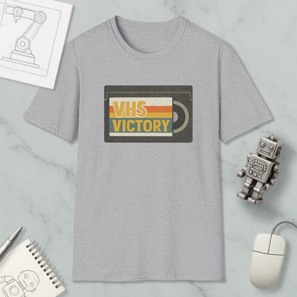 a gray t-shirt with a graphic design, a small robot, a mouse, and a notebook on a marble surface.
