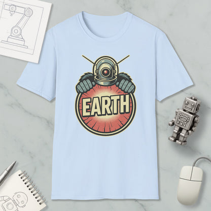 a light blue t-shirt with a graphic design of a robot or alien figure holding a red and orange circle with the word "EARTH" written on it. The t-shirt is placed on a marble surface, along with a computer mouse, a pen, and a notebook.